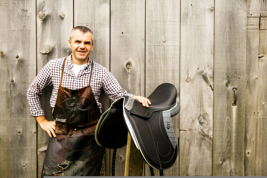 A man showing of a black leather CWD Sellier saddles highlighting the quality stitching and premium materials.