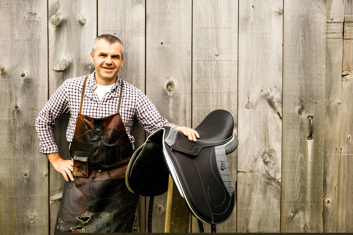 A saddler showing of a black leather CWD Sellier saddles highlighting the quality stitching and premium materials.