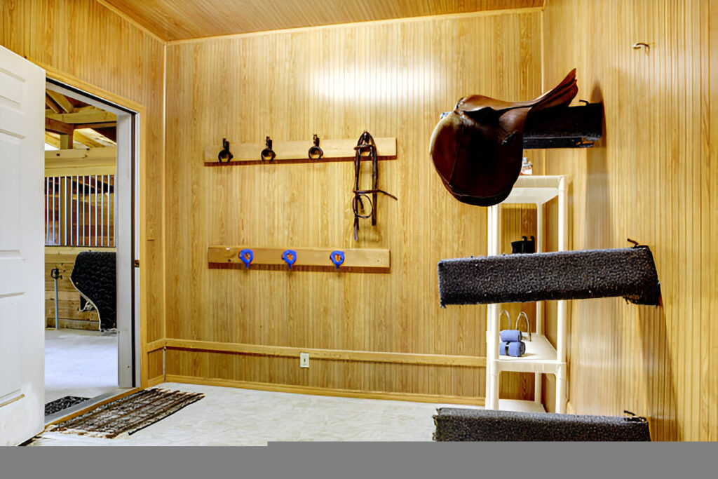 Elegant mahogany-finish freestanding wood saddle holder supporting a leather saddle in a tack room.
