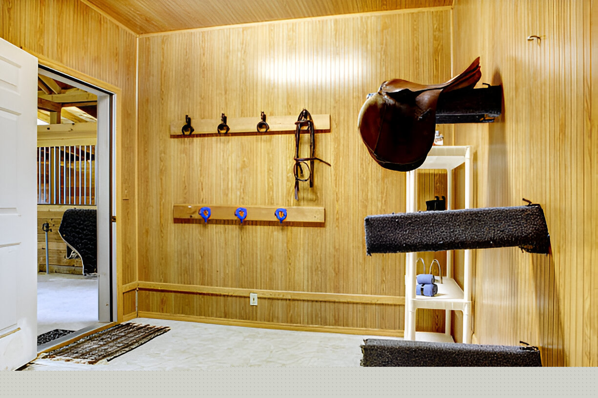 Elegant mahogany-finish freestanding wood saddle holder supporting a leather saddle in a tack room.